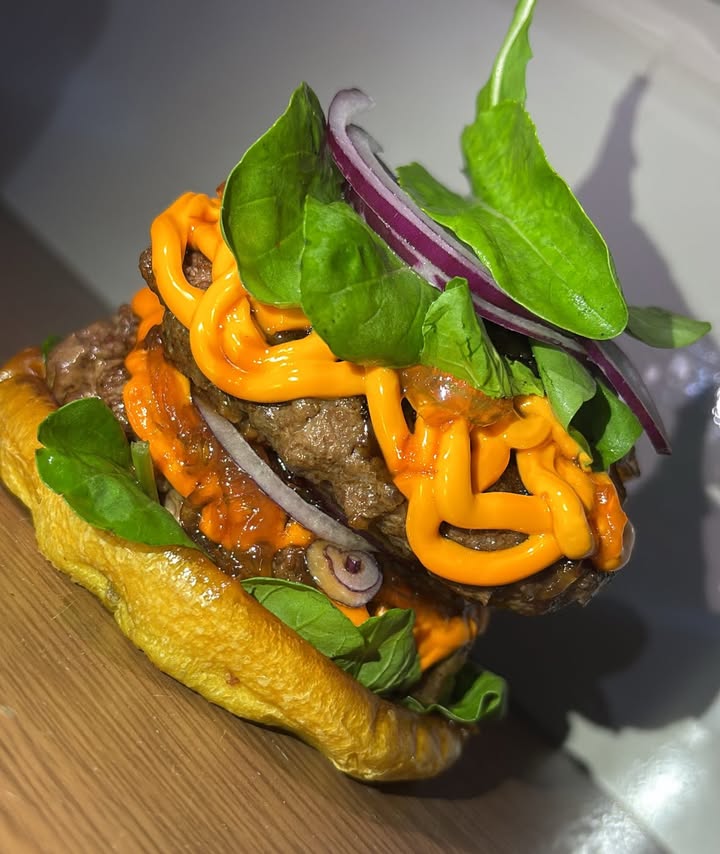 Hambúrguer artesanal com folhas frescas e molho cheddar